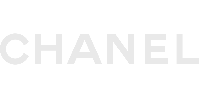 The image displays the word “CHANEL” in large, thin, light gray capital letters on a light gray background. This minimalist style reflects Vu, la lunetterie à Montréal avec le plus grand inventaire de montures à Montréal.